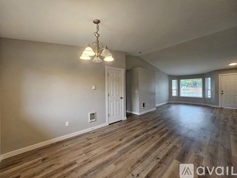 A room with wooden flooring and a chandelier hanging from the ceiling.