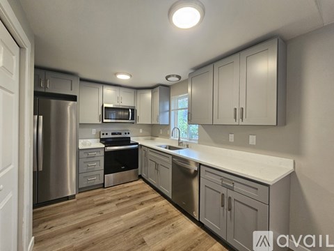 A kitchen with a refrigerator, microwave, oven, and sink.