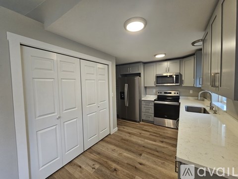 A kitchen with white cabinets and a wooden floor.
