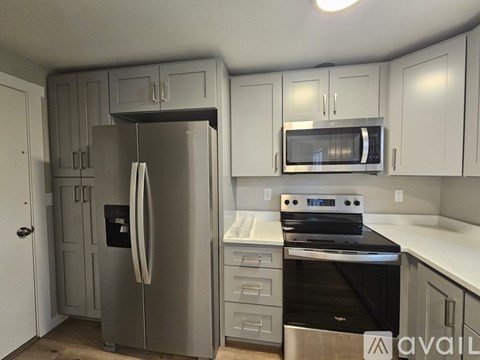 A kitchen with a stainless steel refrigerator, microwave, and stove.