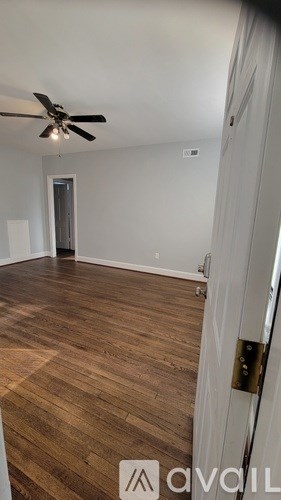 A room with a ceiling fan and wooden flooring.