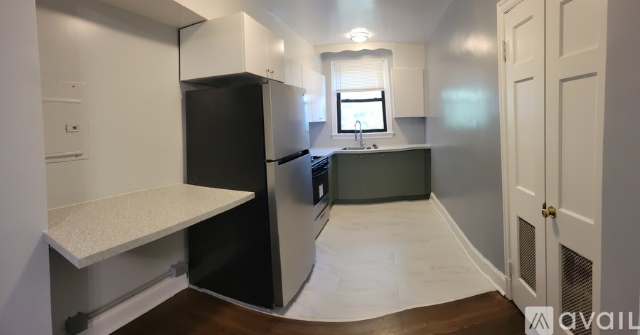 A kitchen with a black refrigerator and white cabinets.