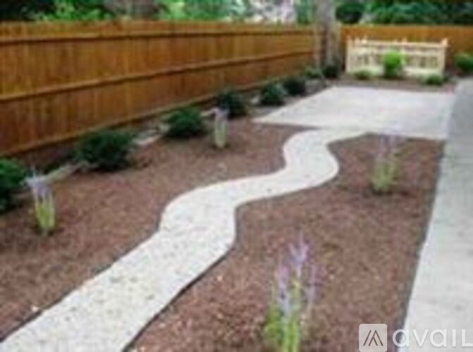 A garden pathway with a wooden fence and purple flowers.