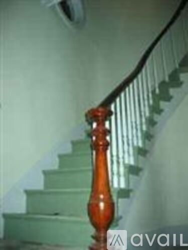 A staircase with a green carpet and a wooden handrail.