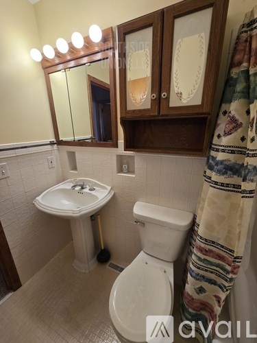 A bathroom with a white toilet, sink, and a mirror with lights above it.