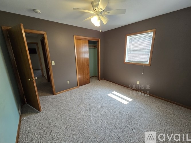 A room with a ceiling fan and a window with blinds.