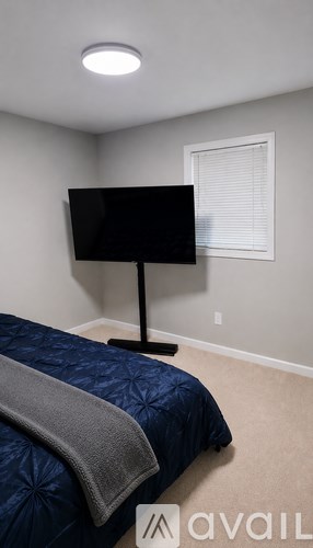 A bedroom with a bed, a television, and a window with blinds.