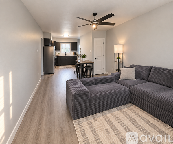 A living room with a grey couch and a ceiling fan.
