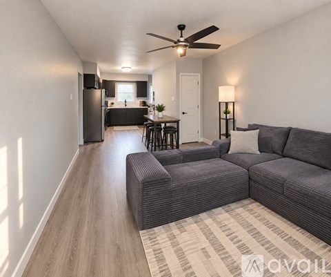 A living room with a grey couch and a ceiling fan.