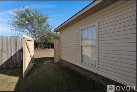 A house with a wooden fence and a tree in the background.