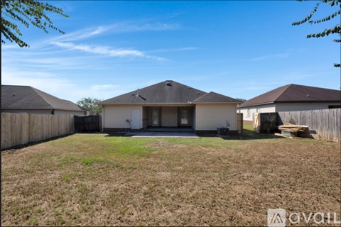 A house with a brown roof and a white wall is surrounded by a fence.