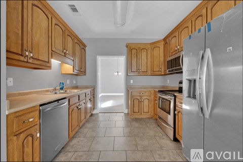 A kitchen with wooden cabinets and a stainless steel refrigerator.