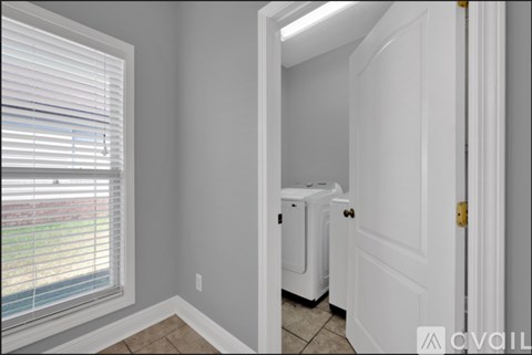 A room with a window and a door leading to a bathroom.
