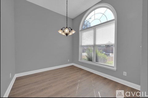 A room with a large arched window and a chandelier hanging from the ceiling.