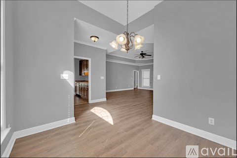 A spacious room with wooden floors and a ceiling fan.