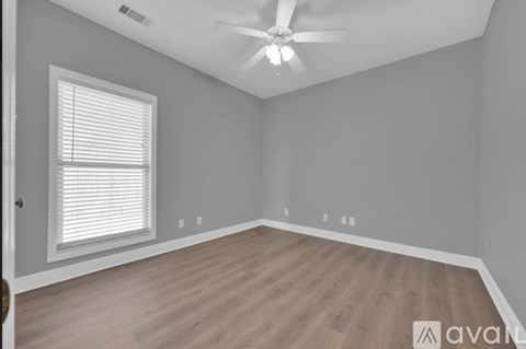 A room with a ceiling fan and a window with blinds.