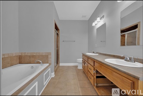 A bathroom with a tub, sink and mirror.
