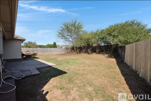 A backyard with a wooden fence and a tree.