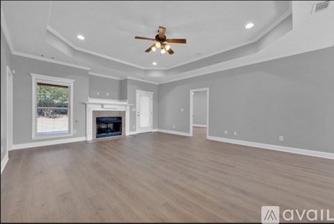 A spacious room with a ceiling fan and a fireplace.