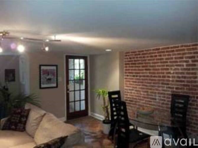 A living room with a couch, chairs, and a brick wall.