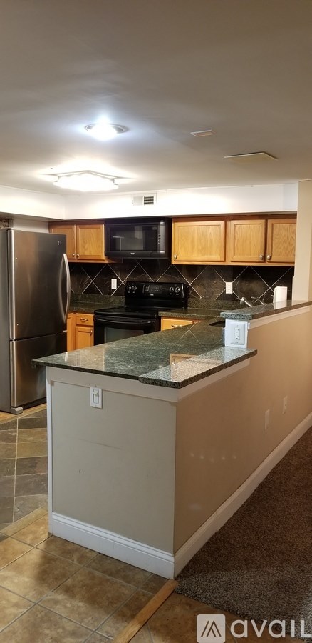 A kitchen with a black stove top oven and a black microwave above it.