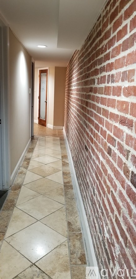A long hallway with a brick wall on one side and tiled flooring.