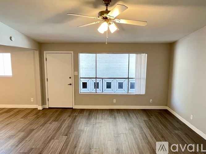 A room with a ceiling fan and wooden flooring.
