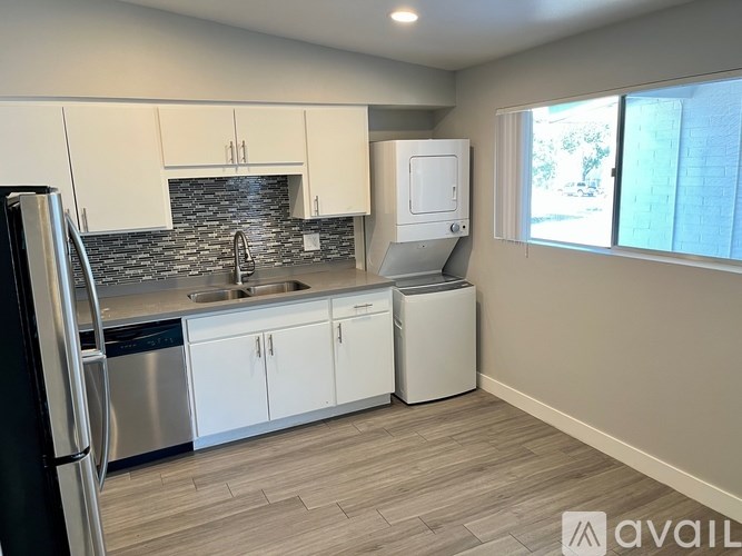 A kitchen with white cabinets and a black refrigerator.