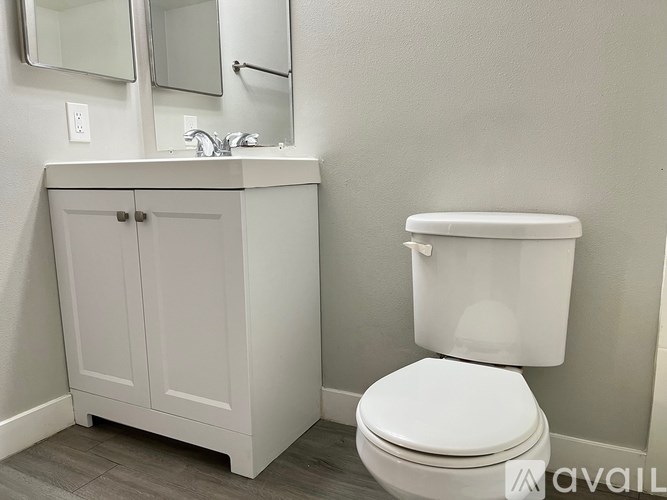 A white toilet sits next to a white cabinet with a sink.