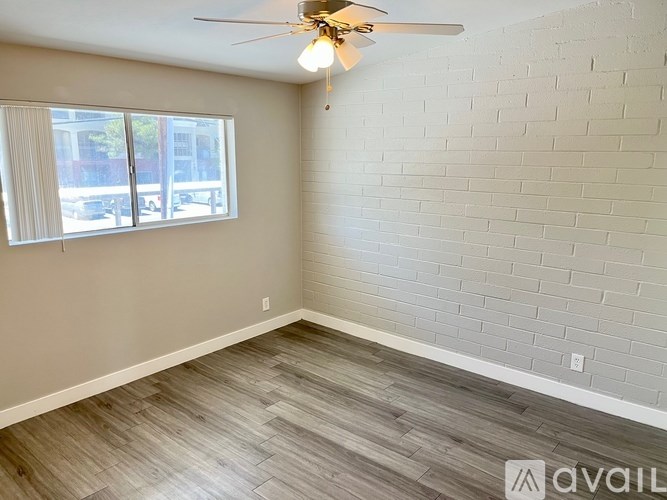 A room with a ceiling fan and a window with blinds.