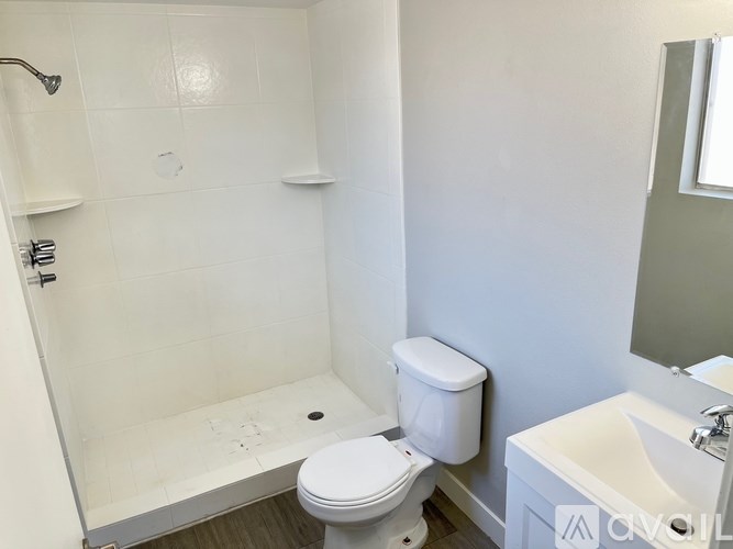 A white toilet in a small bathroom with a white shower.