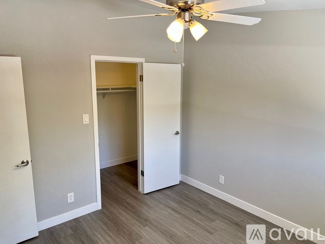 A room with a ceiling fan and a doorway leading to another room.