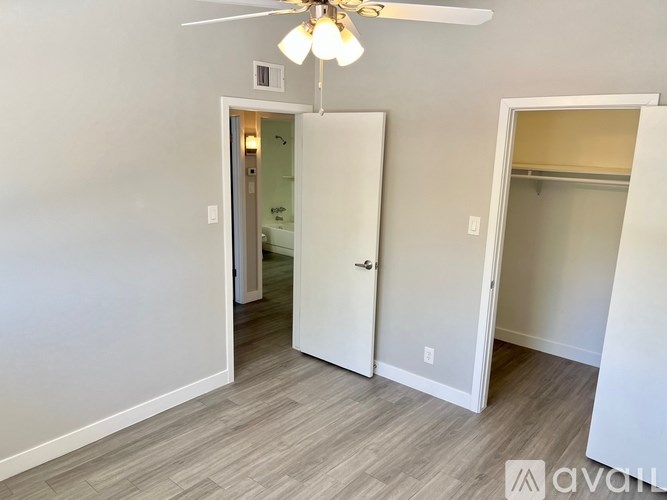 A room with a ceiling fan and two open doors.