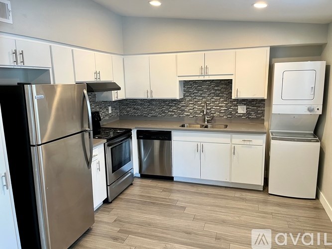 A kitchen with a refrigerator, oven, sink, and a black stone backsplash.