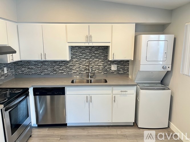A kitchen with white cabinets and a black and white backsplash.