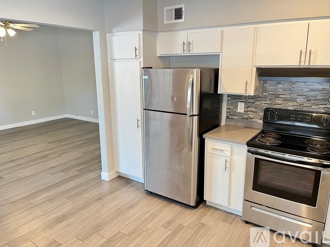 A kitchen with a stainless steel refrigerator and oven, and a wooden floor.