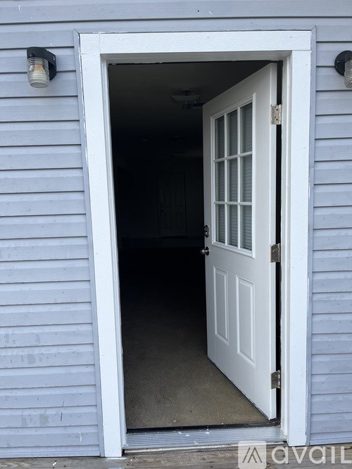 A white door is open to a dark interior.