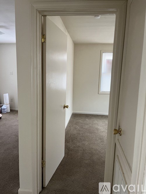 A hallway with a carpeted floor and white walls.
