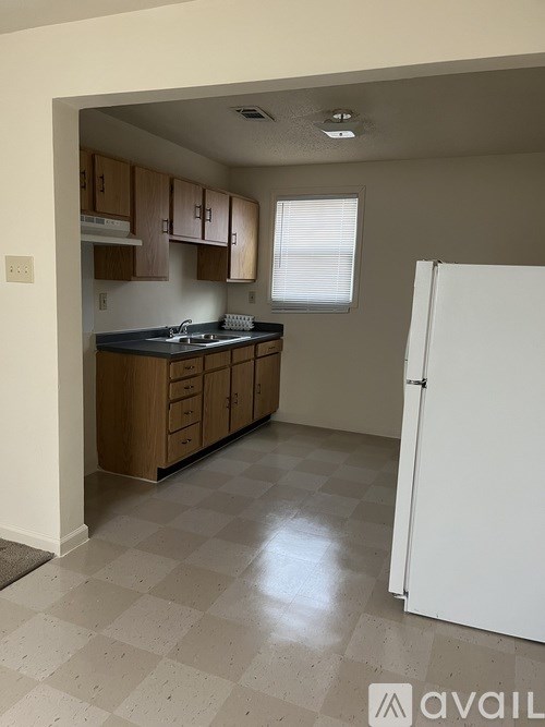 A kitchen with a white refrigerator and wooden cabinets.