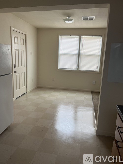 A kitchen with a checkered floor and a window with blinds.