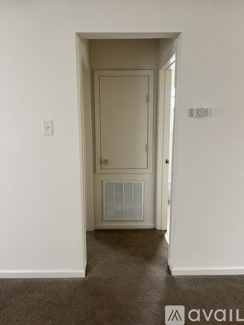 A hallway with a door and a carpeted floor.