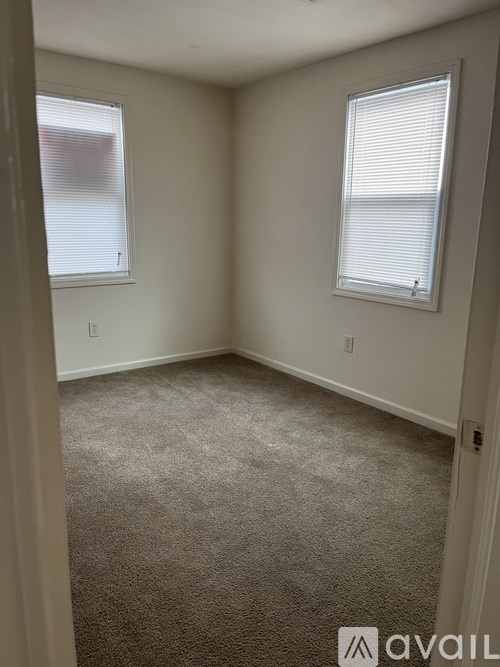 A carpeted room with a window and a door.