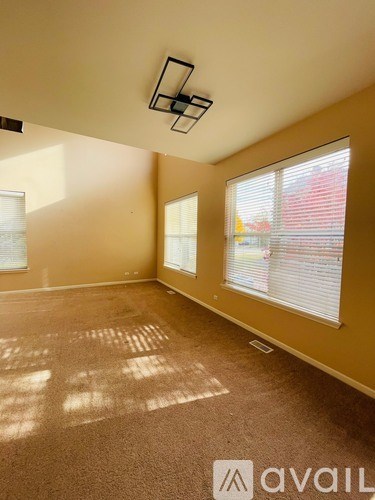 A room with a carpeted floor and a window with blinds.