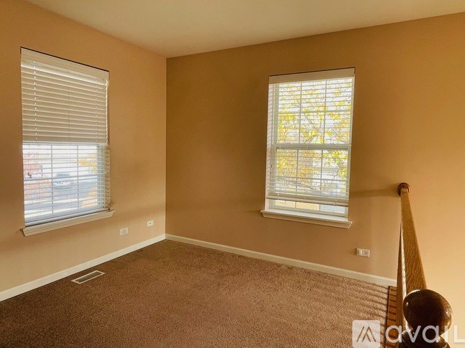 A room with two windows and carpeted flooring.