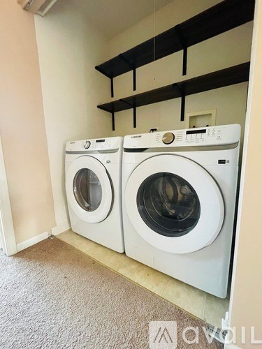 Two white front loading washing machines in a laundry room.