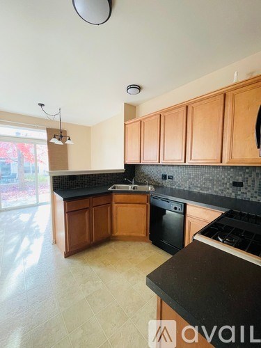 A kitchen with wooden cabinets and black countertops.