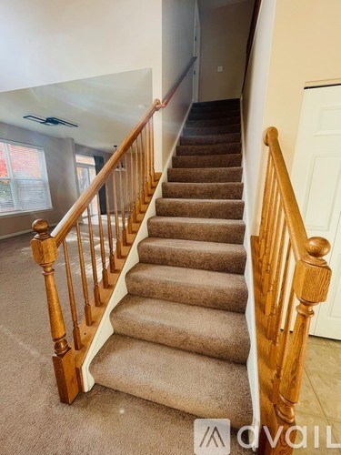 A staircase with wooden balusters and beige carpeted steps.