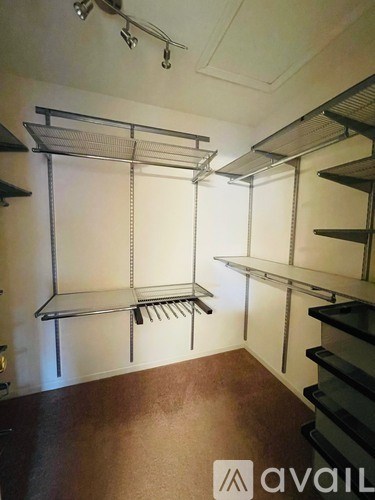 A room with a brown floor and white walls has a shelving unit with a rack and a shelf.