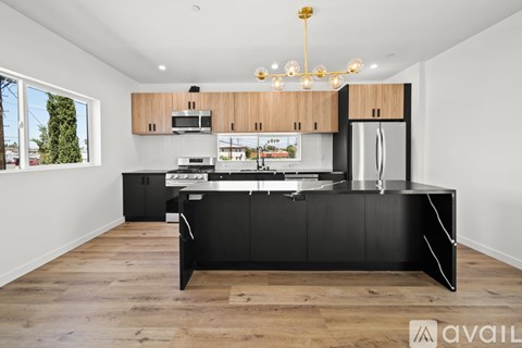 A modern kitchen with black cabinets and a wooden floor.