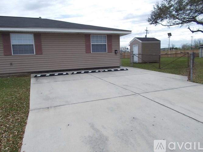 A house with a brown siding and a grey roof with a driveway in front.
